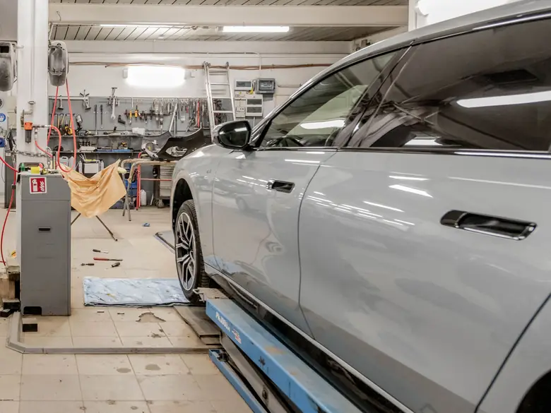 Coche gris sobre un elevador en un taller mecánico, con el panel de herramientas al fondo